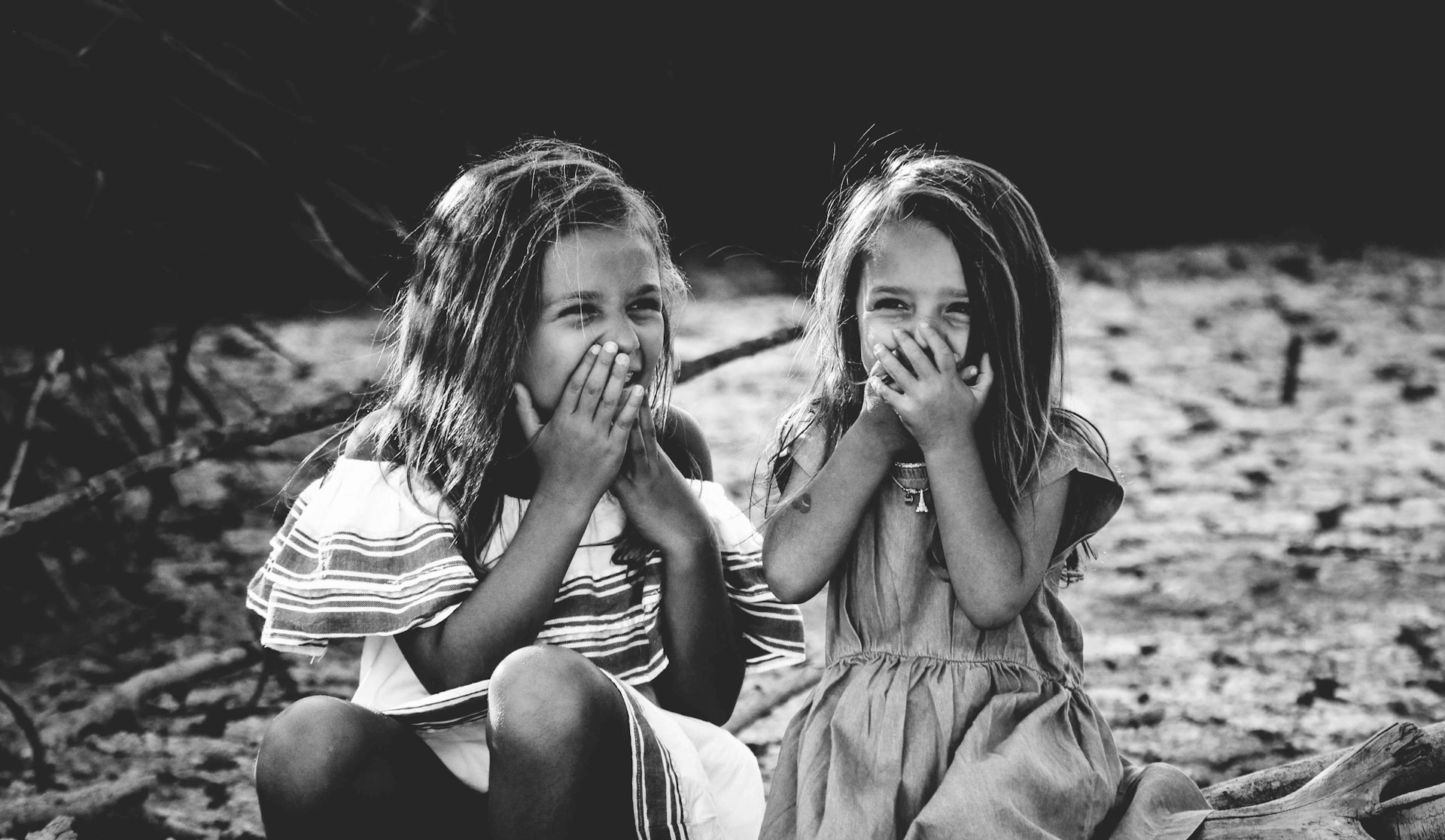 grayscale photography of two girls closing their mouths